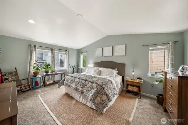 Primary bedroom has warm colors, vaulted  ceilings & lots of natural lighting.