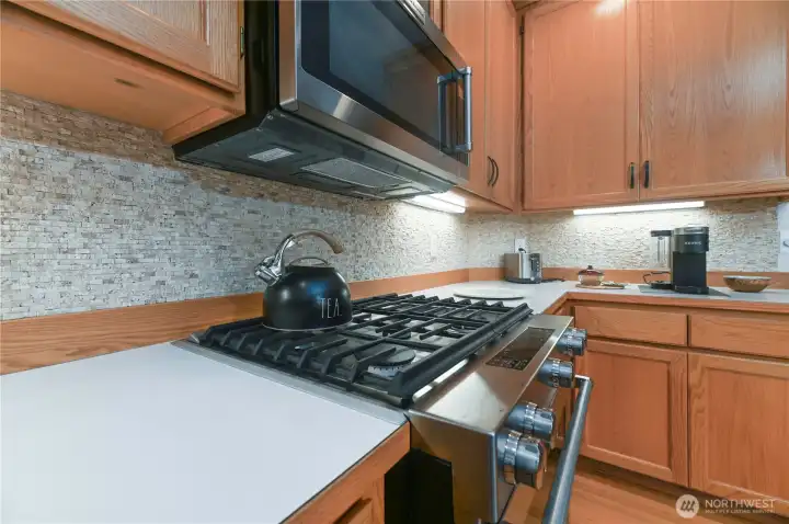 Gas range in the kitchen. Most appliances are stainless steel.