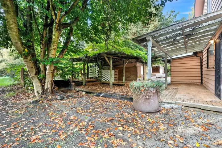 Photo shows side of the house with the private well outbuilding and deck.