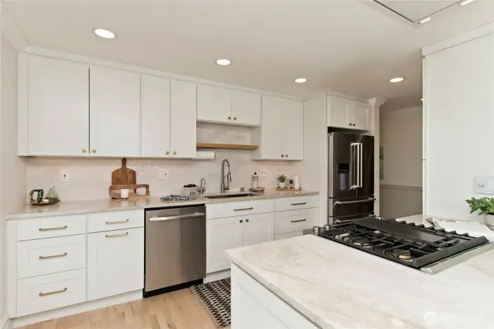 Premium JennAir and KitchenAid appliances throughout. Under-cabinet lighting enhances workspace visibility.