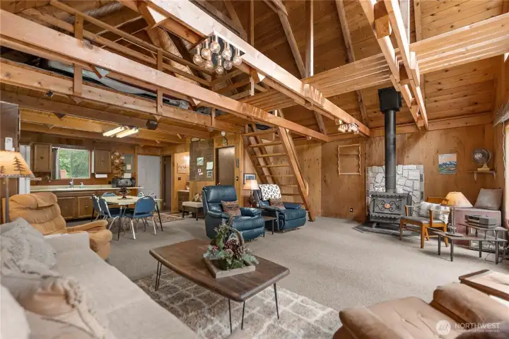 Spacious open-concept living room with rustic wood interiors, loft access, and inviting gathering spaces ideal for relaxing after outdoor adventures.