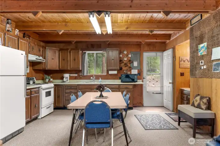 Bright and comfortable kitchen with large picture window, plenty of prep space, and inviting dining area overlooking the forested setting.