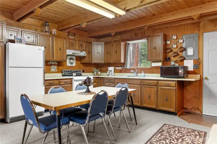 Spacious open-concept kitchen and dining area with soaring wood ceilings, natural light, and cozy lodge-style charm throughout.
