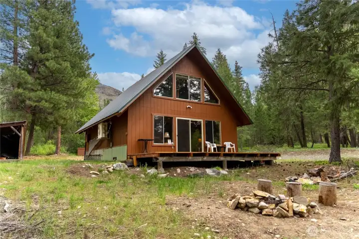 Cozy front deck overlooking the wooded setting with space to relax, entertain, and enjoy the peaceful mountain surroundings. Outdoor fire pit area creates the perfect gathering spot under the trees.