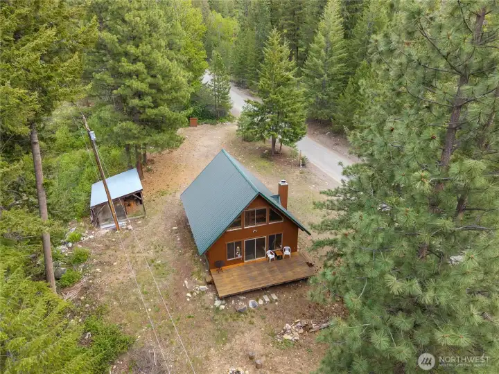 Aerial perspective of the property showing the cabin’s tucked-away setting, surrounding forest, and spacious outdoor living area.