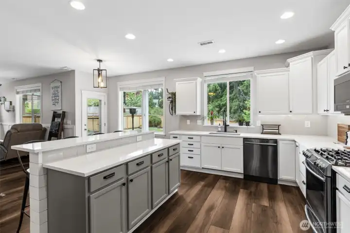 Large updated kitchen with island and raised bar, quartz countertops, designer paint, custom under mount cabinet lighting and modern amenities.