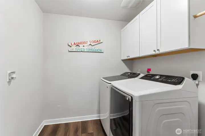 Large laundry room conveniently located upstairs features cabinets for storage