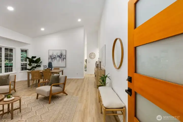 The entry welcomes with a vibrant wood accent door, wide-plank flooring, and clean white walls. The entry welcomes with a vibrant wood accent door, wide-plank flooring, and clean white walls.