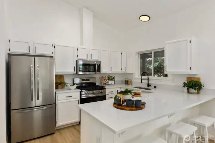 A generous center island with bar seating and sleek countertops anchors this well-appointed kitchen. A generous center island with bar seating and sleek countertops anchors this well-appointed kitchen.