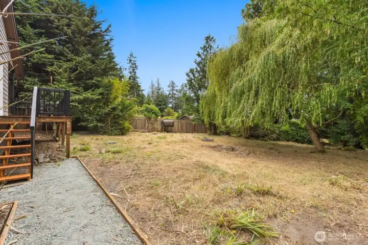 A stone path winds through the spacious, tree-shaded backyard, offering a peaceful outdoor escape. A stone path winds through the spacious, tree-shaded backyard, offering a peaceful outdoor escape.