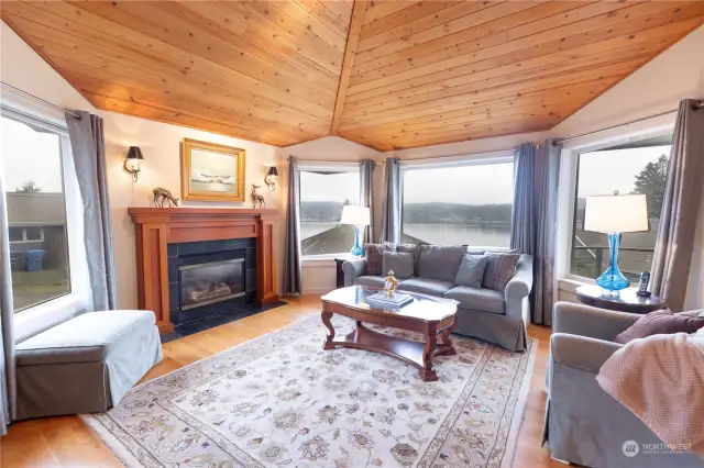 Gorgeous knotty pine vaulted ceilings in living and dining areas showing views and gas fireplace with custom straight grain fir mantel