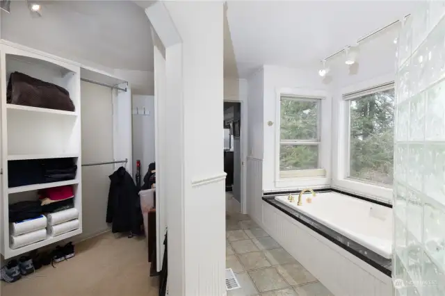 Primary bath with soaking tub, tile floors, and walk in custom closet