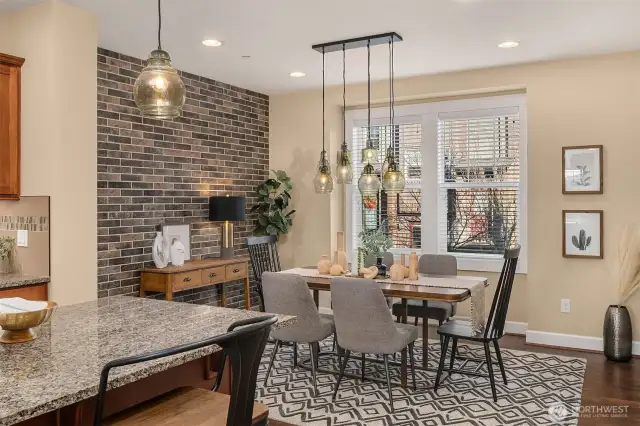 Another view of the dining area which showcases the brick accent wall and hanging glass light fixtures.