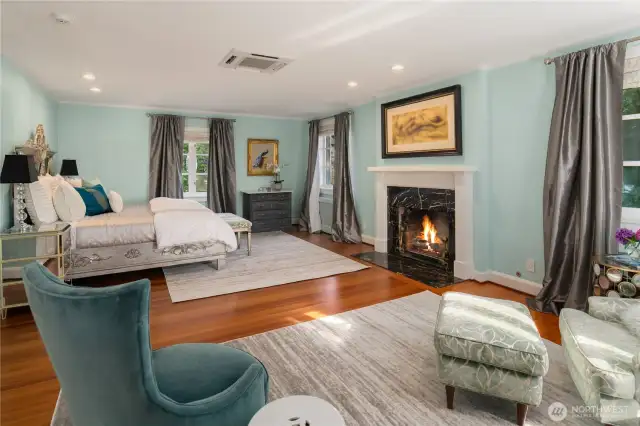 The primary bedroom is anchored by a fireplace and has sets of windows that face both sides of the home. A walk-in closet and master bathroom are through the arched doorway.