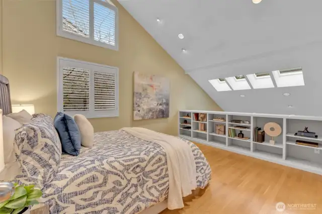 Upstairs is the primary bedroom, offering vaulted ceiling, built-in bookcase, hardwood floors