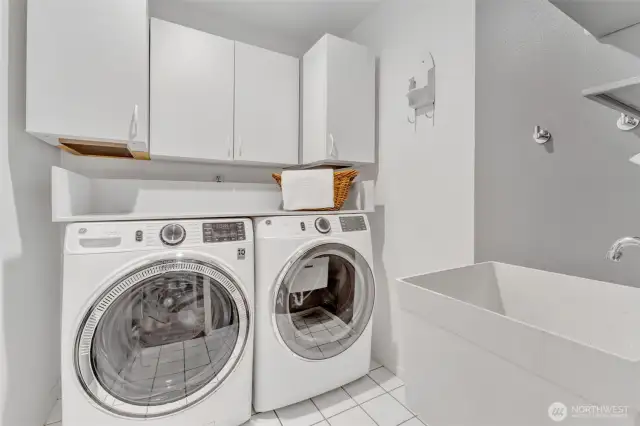 Laundry room offers storage, utility sink and tiled floors