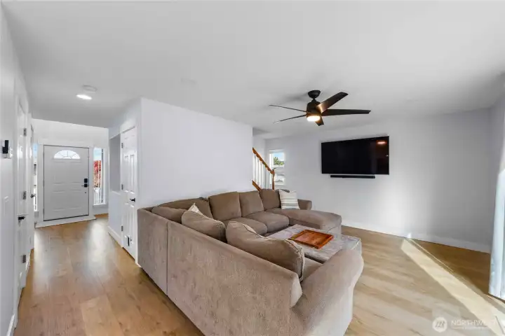 Living room has a modern ceiling fan and is filled with natural light.