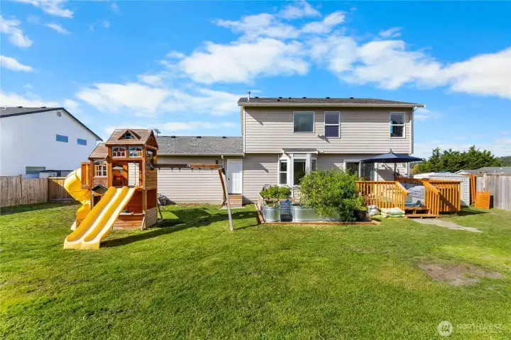 Large back yard comes with play set and garden that produces fruits and vegetables in containers.