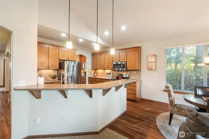 The kitchen offers a breakfast bar and casual dining space with view of the tranquil trees