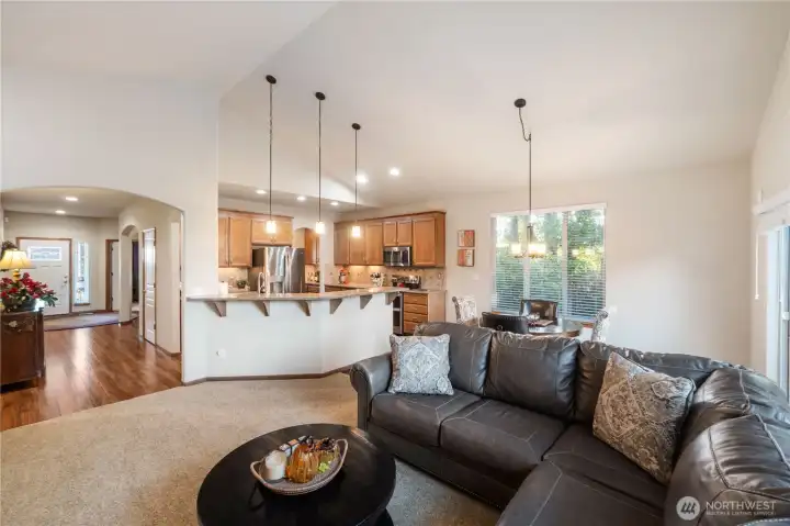 The great room with soaring vaulted ceilings offers plenty of comfortable space. The fireplace with tile surround & wood mantle is to the left