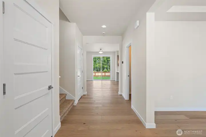 Hardwoods run the length of the hallway for a seamless, open flow including dining and kitchen.