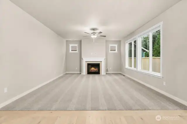 Living room featuring a crisp gas fireplace with tile surround and mantle. A ceiling fan with integrated lighting enhances comfort and functionality.
