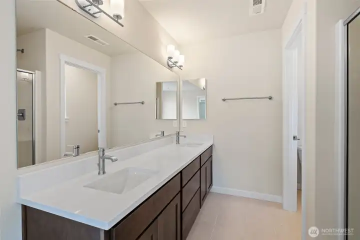 Primary bathroom with tile floors and quartz counter tops on dual sink vanity plus medicine cabinet.