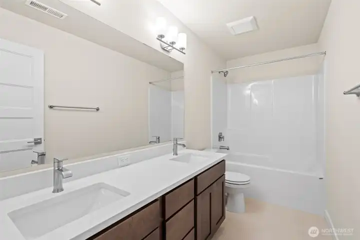 The main bathroom on the second level features a dual undermount sink vanity and sleek quartz countertops.