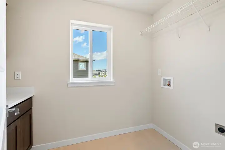 Laundry room conveniently located on the second level, featuring upper and lower cabinets along with a hanging shelf.
