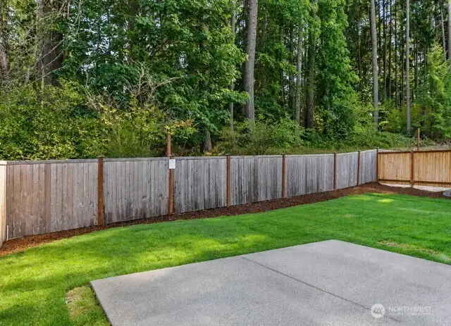 The fully fenced perimeter adds security and definition, while the lush forest backdrop beyond the fence delivers a serene, natural buffer.