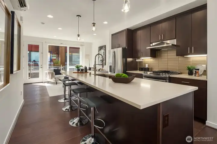 Spacious kitchen with slab quartz countertops, massive center island, full height backsplash & SS appliances.