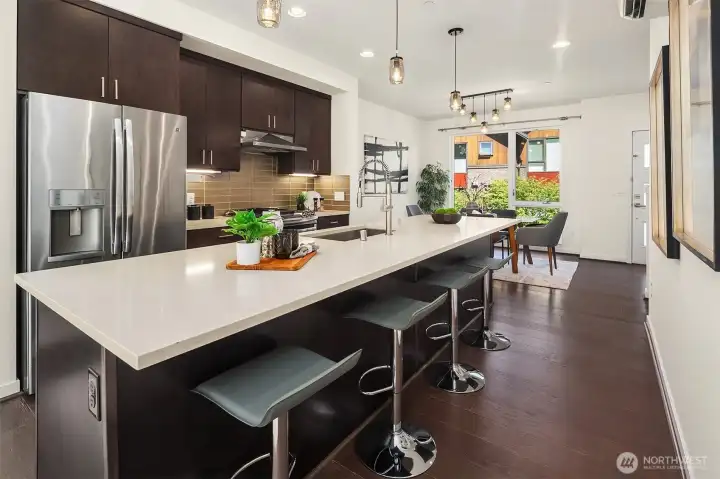 Spacious kitchen with slab quartz countertops, massive center island, full height backsplash & SS appliances.