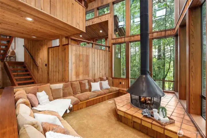 Custom living space flanked by walls of windows situated around fire