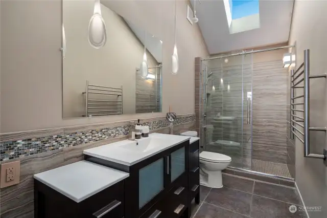On the upper level, there's a hall bathroom illuminated by skylights and equipped with a heated towel rack.