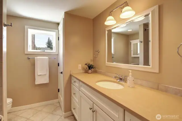 The lower level bath includes a full tub and a neutral stone floor.