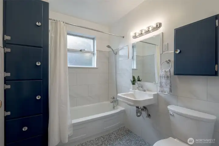 Bathroom with porcelain penny round tile on floor and large porcelain subway tile on walls. More custom built-ins and medicine cabinet for ample storage.