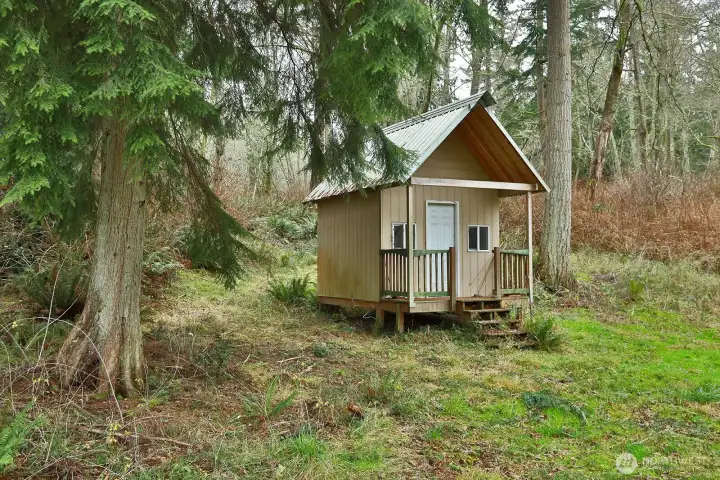 There is a small cabin within site of the patio located in the woods behind the house.  The interior is finished.