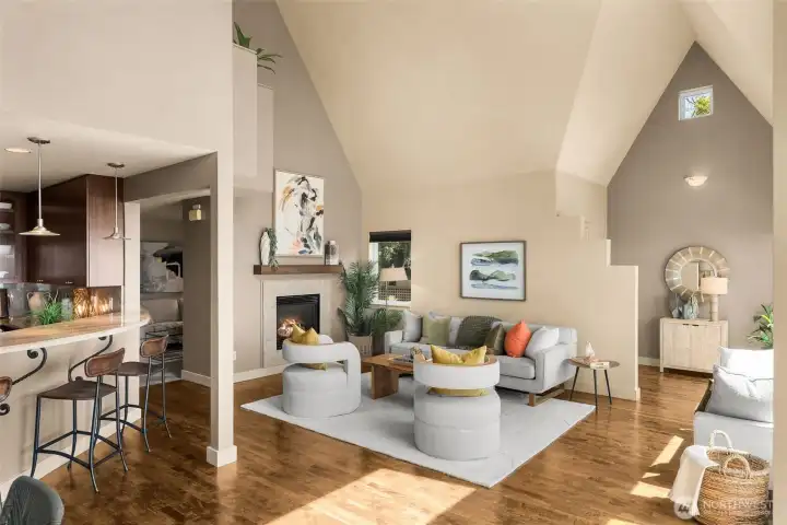 Main level formal living room, showcasing a gas fireplace, vaulted ceilings & beautiful maple hardwood floors