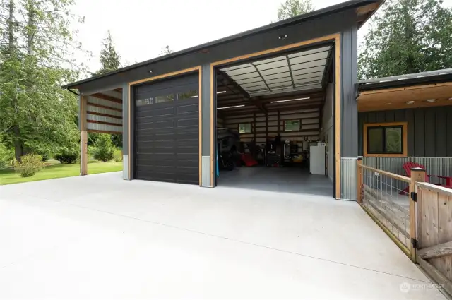 Garage/shop and carport with large concrete pad.  Fence and gate on right lead into entrance to cottqge, yard and covered hot tub area.