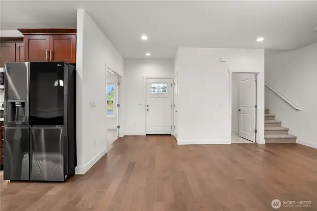 Bright and inviting entryway with warm hardwood floors, modern recessed lighting, and an open layout that seamlessly connects to the main living spaces.