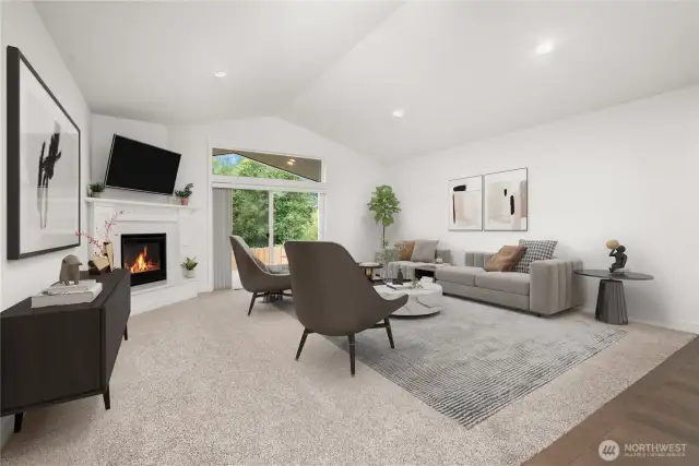 Light-filled living room with vaulted ceilings, cozy corner fireplace, and sliding doors leading to a private backyard retreat. Virtually staged.