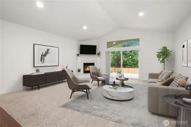 Expansive living room with vaulted ceilings, a cozy fireplace, and large sliding doors opening to a serene, tree-lined backyard. Virtually staged.