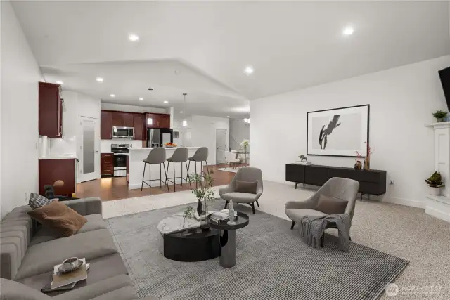 Open-concept design with seamless flow from the spacious living room to the modern kitchen, featuring rich cabinetry, stainless steel appliances, quartz counters, and a breakfast bar. Virtually staged.