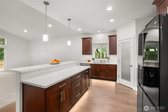 Bright and functional kitchen with expansive counter space, under-cabinet lighting, rich wood cabinetry, and a large breakfast bar perfect for entertaining.