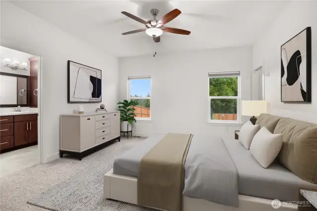 Spacious primary bedroom with plush carpeting, ceiling fan, and large windows overlooking the backyard, complete with an en-suite bath and large walk-in closet. Virtually staged.