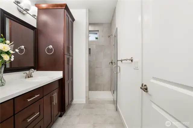 Primary en-suite featuring a dual-sink vanity with abundant storage and a walk-in tiled shower with glass door.