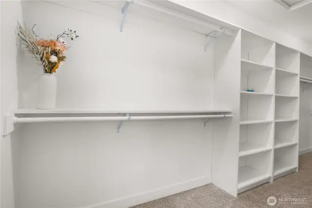 Expansive walk-in closet in the primary bedroom with built-in shelving and double hanging rods for optimal storage and organization.