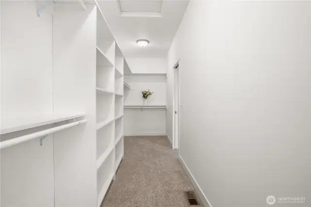 Large walk-in closet in the primary bedroom with extensive shelving, double hanging rods, and ample space for storage and organization.