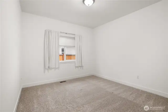 Comfortable secondary bedroom with plush carpeting and a bright window for natural light.
