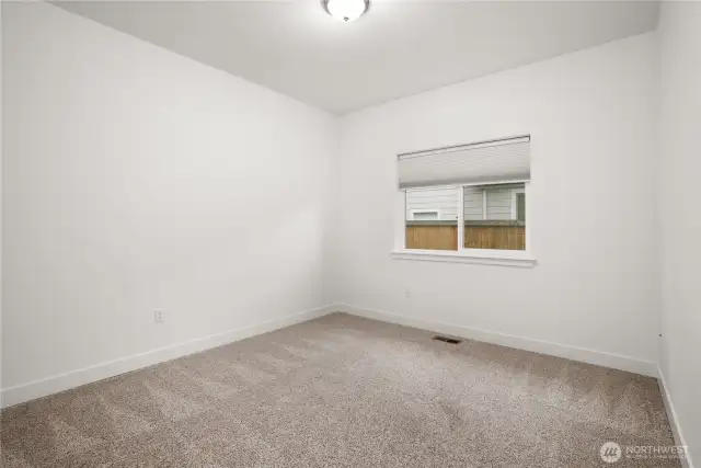 Second of the two non-primary bedrooms with plush carpeting and a large window for natural light.